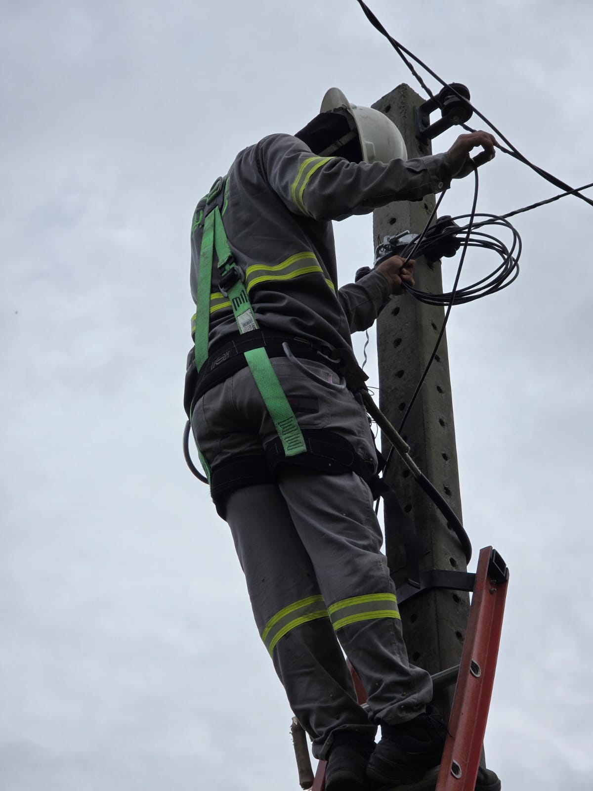 Equipe efetuando lançamento de cabos no poste